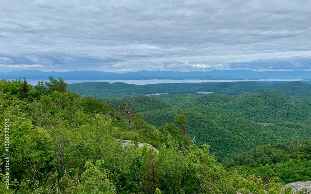 Obraz premium Scenic view of lush green hills and a distant lake.