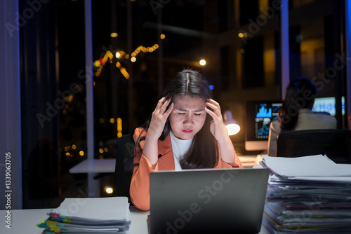 Young business woman is working overtime and feeling stressed and tired from work in the office late at night