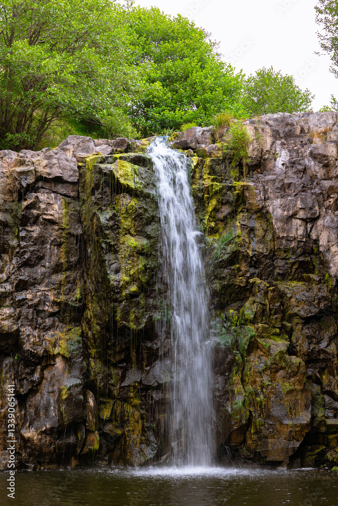 Obraz premium A rocky waterfall in the dry season with trees on the background