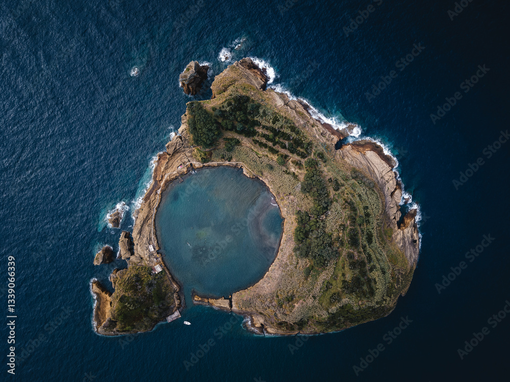 Aerial frontal view of Islet of Vila Franca do Campo in the Azores, showcasing its circular lagoon surrounded by lush greenery and the Atlantic Ocean.