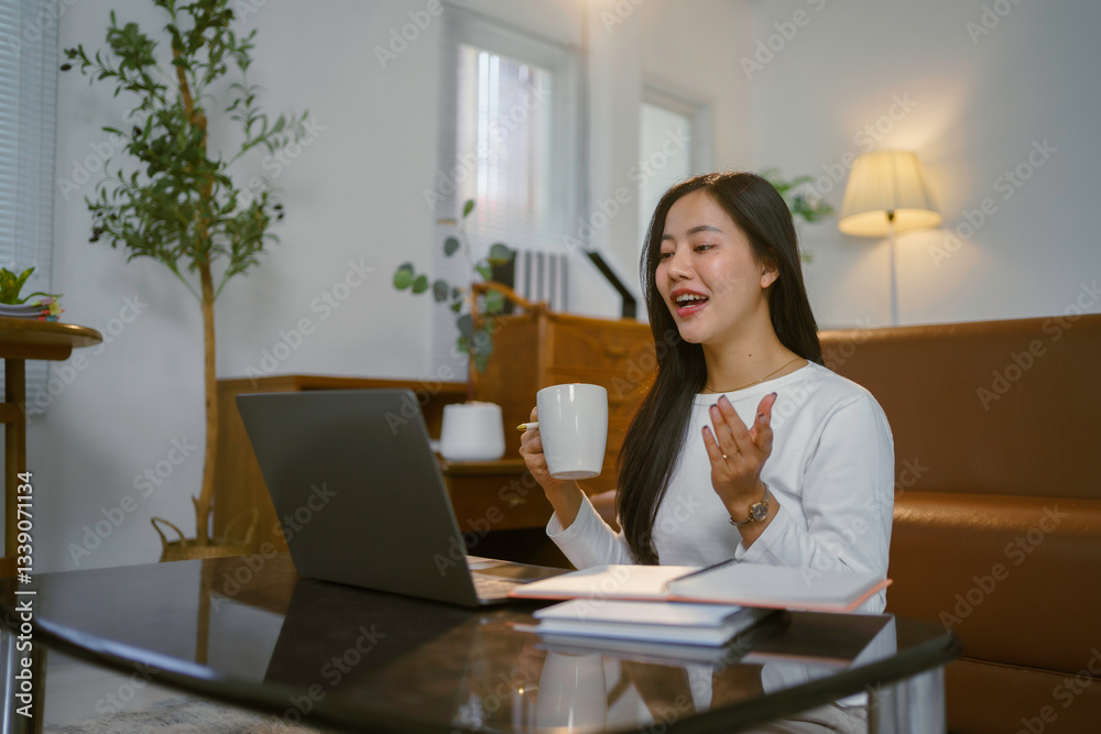 Young Asian woman drinking coffee and making a video call on laptop while working from home Young Asian woman drinking coffee and making a video call on laptop while working from home