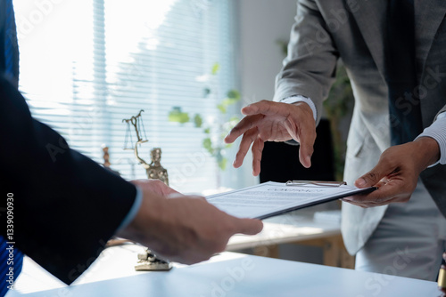 Two lawyers in suits reviewing and exchanging legal documents, discussing contract terms and conditions in a bright office