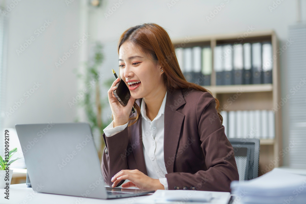 Professional businesswoman working simultaneously, handling phone conversation and digital tasks at contemporary workplace Professional businesswoman working simultaneously, handling phone conversation and digital tasks at contemporary workplace