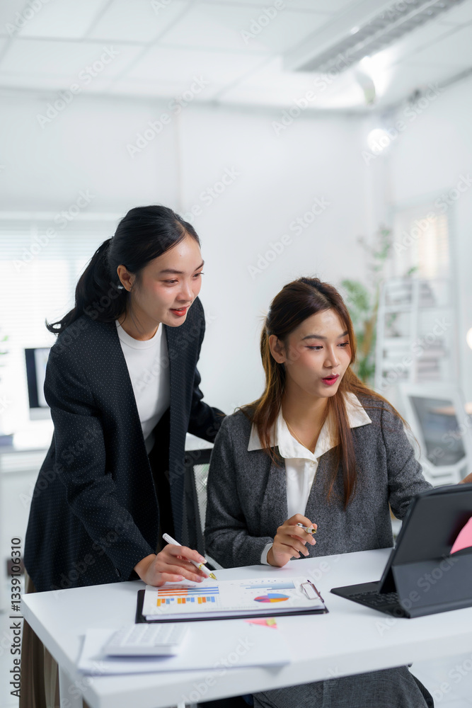 Two asian businesswomen analyzing financial charts and graphs using tablet computer in office, discussing company growth and financial performance Two asian businesswomen analyzing financial charts and graphs using tablet computer in office, discussing company growth and financial performance