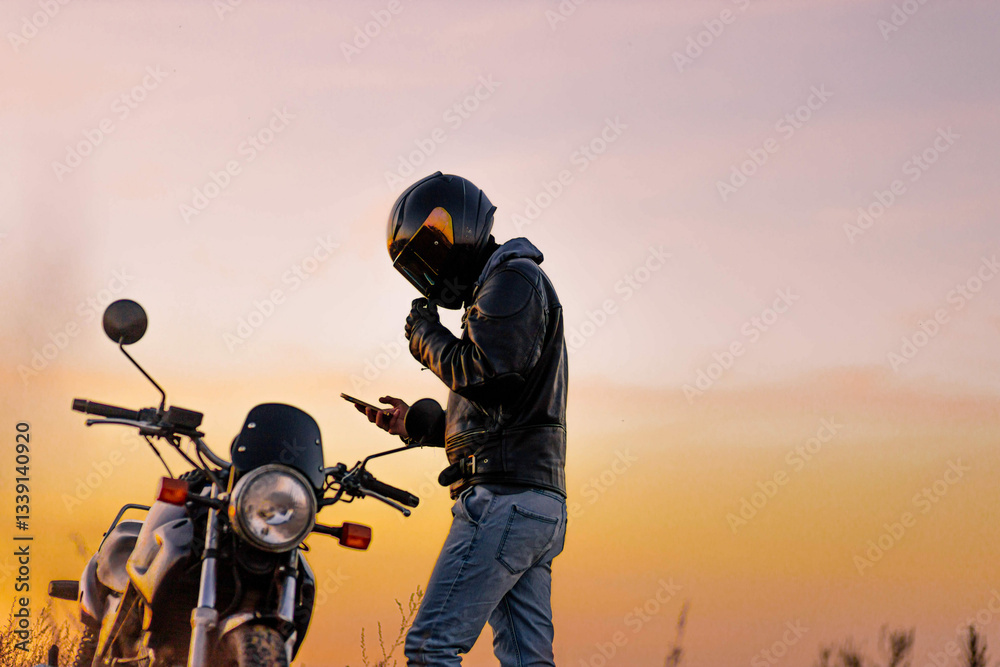 motorcyclist in leather jacket at sunset with helmet