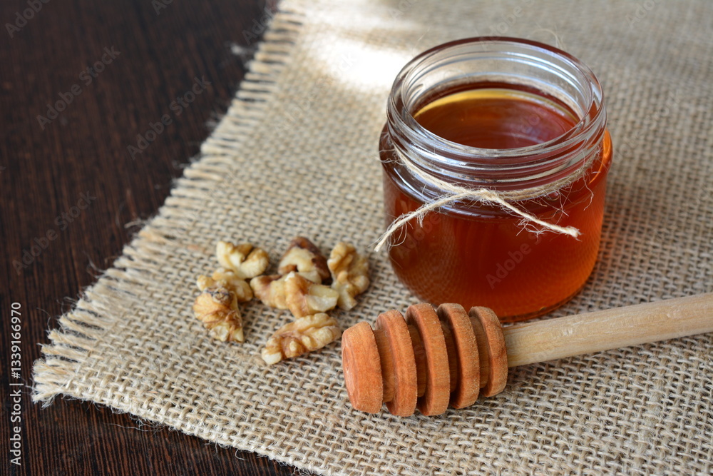 Jar of Honey with Walnuts and Wooden Dipper on a Rustic Background Jar of Honey with Walnuts and Wooden Dipper on a Rustic Background