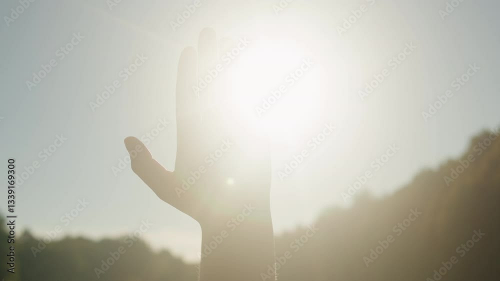 Hand of young woman at sunset close-up. Sun between the hands of tourist girl. Silhouette of happy dreaming female pulls her hand to the sun