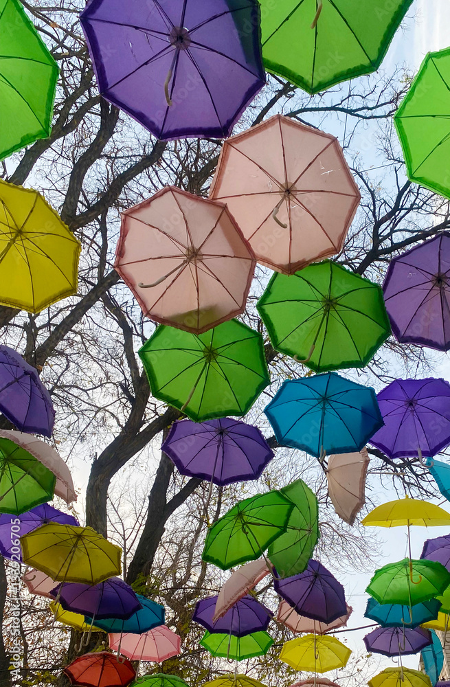 Naklejka premium Colorful umbrellas decorate the street, view from below, background concept