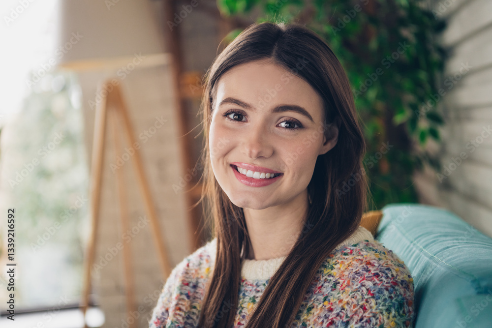 Cheerful young woman sitting indoors in a stylish living room with natural daylight, smiling warmly in a colorful sweater and casual style Cheerful young woman sitting indoors in a stylish living room with natural daylight, smiling warmly in a colorful sweater and casual style