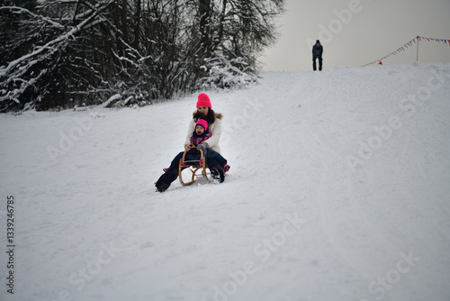 Obraz na płótnie Two girls are tobogganing downhill on snowy hill in winter w salonie