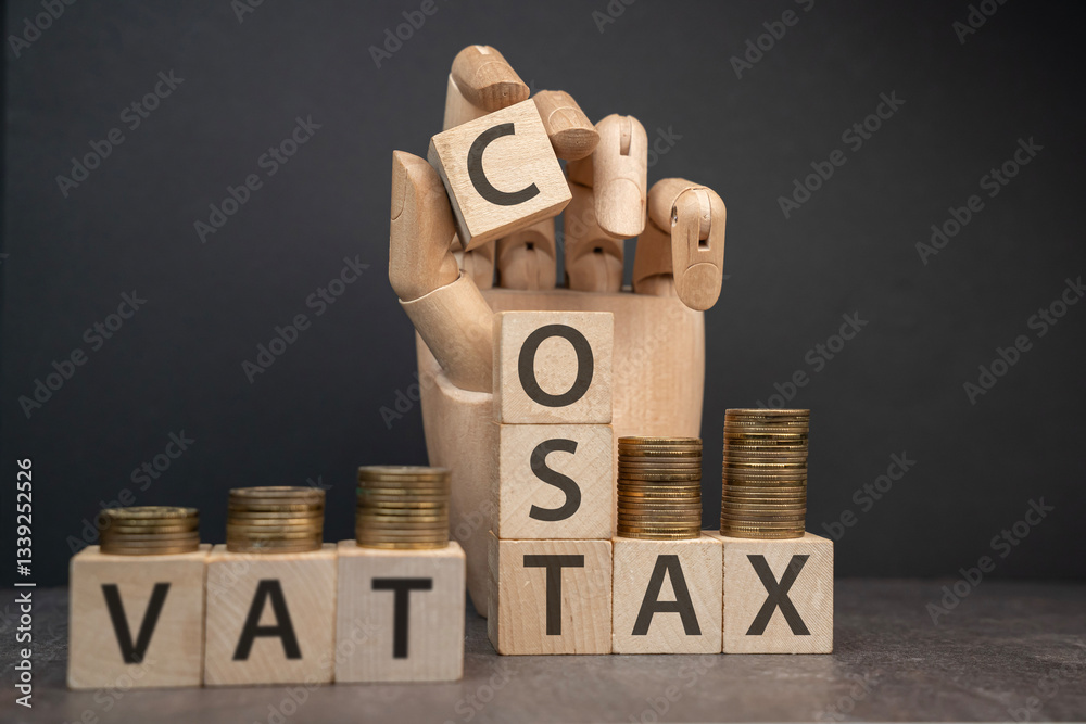 sztuczna dłoń układająca napisy dotyczące finansów: VAT, COST, TAX