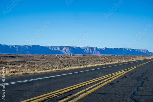 Das Bild zeigt eine weitläufige Autobahn, die sich durch eine wüstenähnliche Landschaft schlängelt. Der Himmelist klar und blau und bietet einen schönen Kontrast zu den erdigen Tönen der Wüste. 