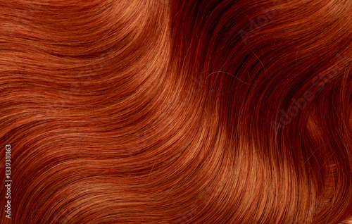 Red hair close-up as a background. Women's long orange hair. Beautifully styled wavy shiny curls. Hair coloring bright shades. Hairdressing procedures, extension.