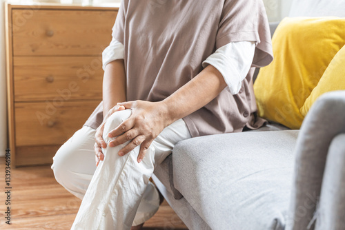 Obraz na plátně Body arthritis muscles stiff problem, aged woman suffering on leg, pain knee from disease chronic, hand massage rubbing joint injury, mature hurt or sore sitting on sofa at home