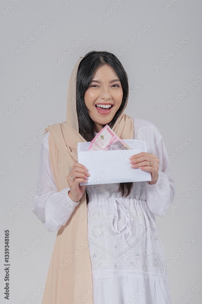 Excited Asian Muslim pregnant woman in a veil hijab holding Eid Al Fitr money gift or THR. Excited Asian Muslim pregnant woman in a veil hijab holding Eid Al Fitr money gift or THR.