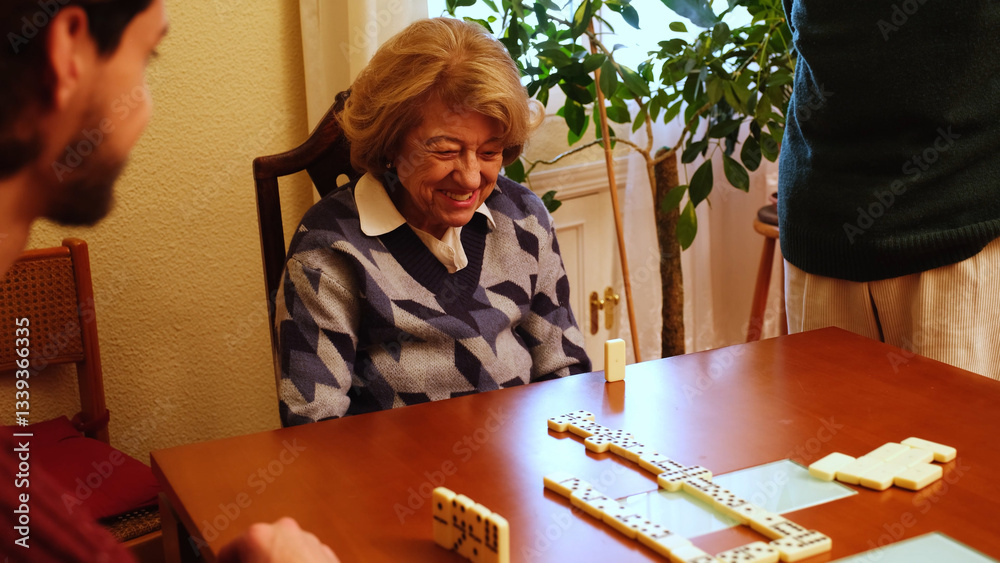 Elderly woman smiling while playing dominoes with her family, enjoying leisure time together