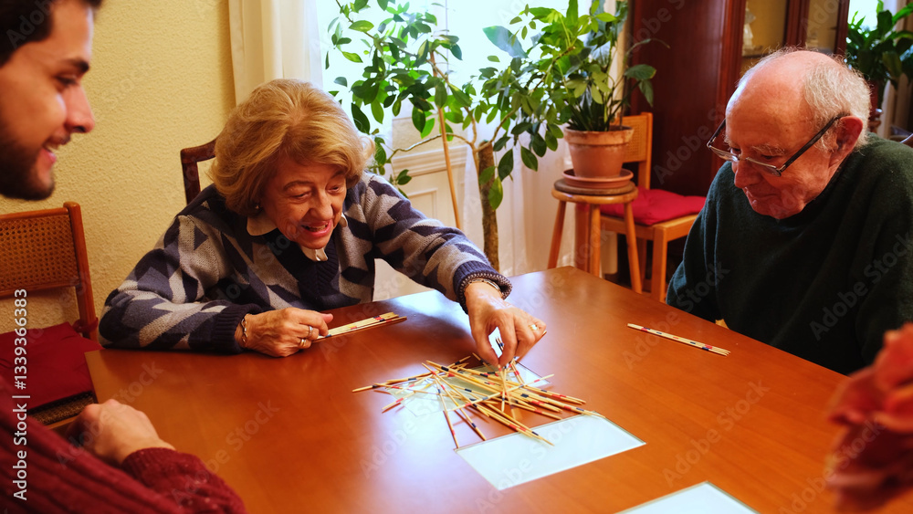 Happy grandmother having fun with her family playing mikado at home