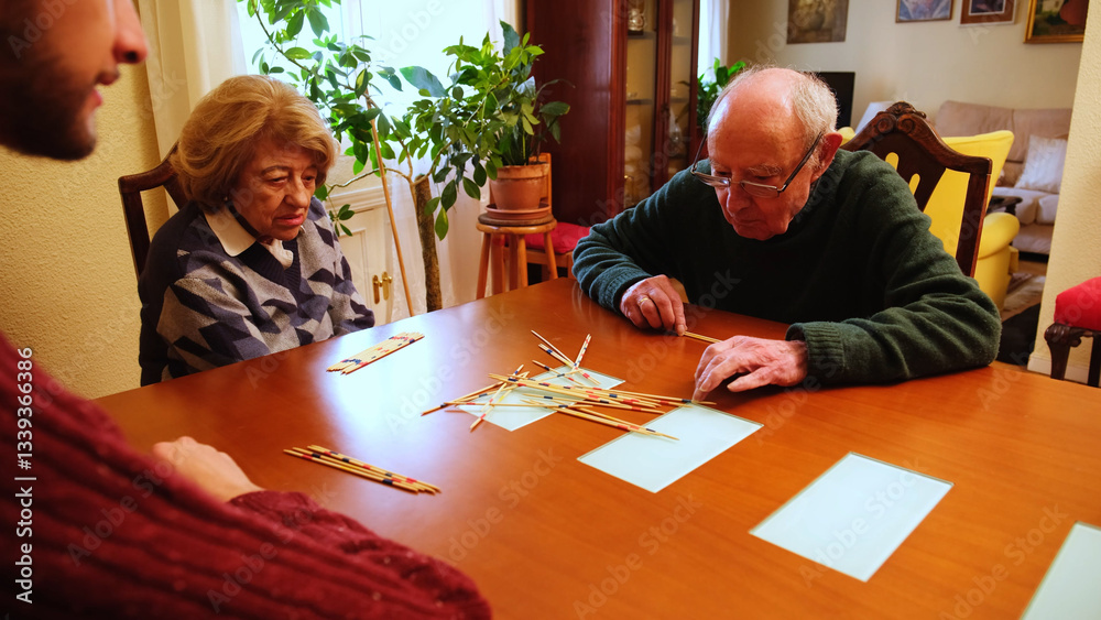 Happy grandmother having fun with her family playing mikado at home