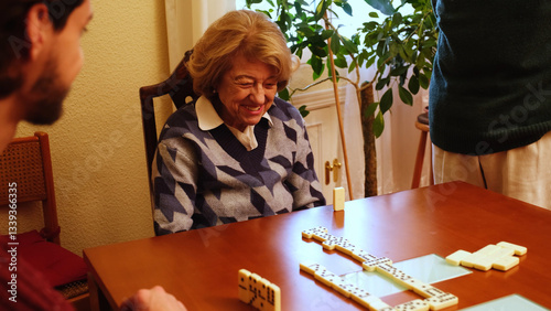 Obraz na płótnie Elderly woman smiling while playing dominoes with her family, enjoying leisure time together w salonie