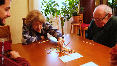 Obraz na płótnie Happy grandmother having fun with her family playing mikado at home w salonie