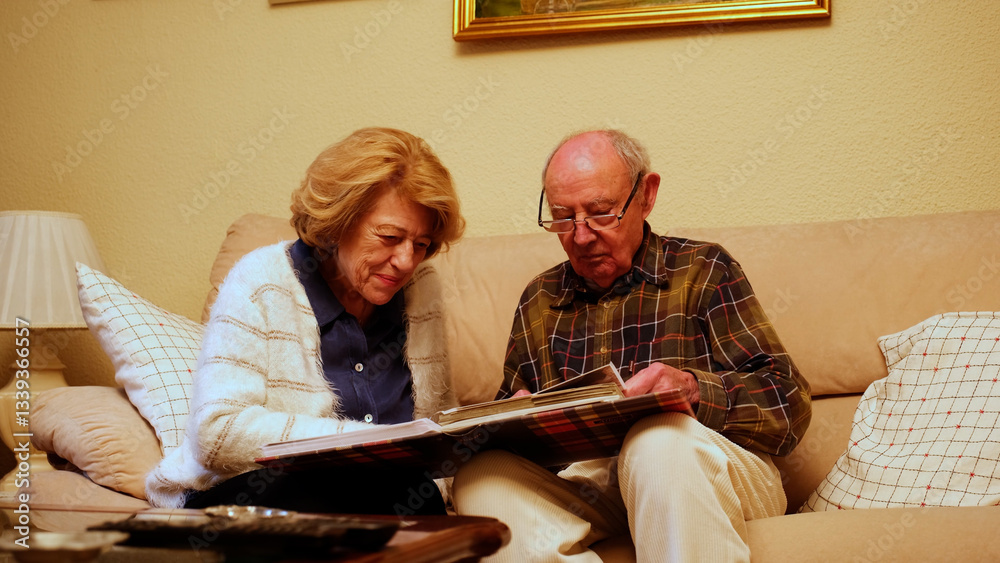 Happy retired couple enjoying their free time together, browsing through old photographs and reminiscing about past memories