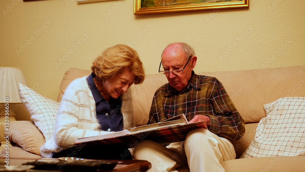 Happy retired couple enjoying their free time together, browsing through old photographs and reminiscing about past memories