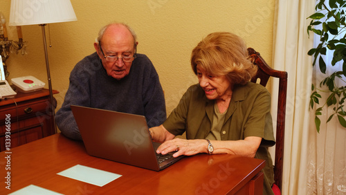Obraz na płótnie Senior couple browsing internet on laptop, happy and smiling, enjoying technology in their home w salonie