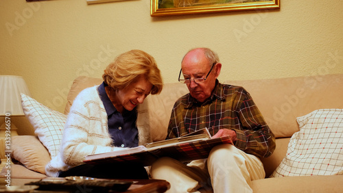 Obraz na płótnie Happy retired couple enjoying their free time together, browsing through old photographs and reminiscing about past memories w salonie