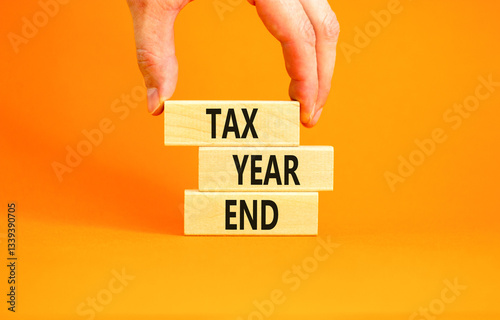 Tax year end symbol. Concept words Tax year end on beautiful wooden blocks. Beautiful orange background. Businessman hand. Business tax year end concept. Copy space.