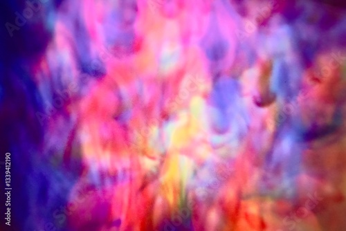 Abstract blur focus vibrant colors flowing with colored inks dispersed in water. The composition consists of shades of blue, red, green and yellow blending and swirling on a light background, creating