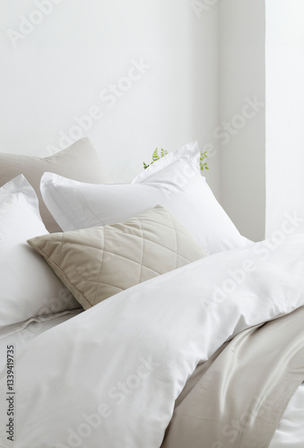 Bed with a fluffy down comforter with a duvet cover, three white pillows, one beige cushion and bedspread. Side view. Close-up photo. Suitable for mockup