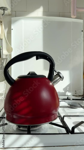 red kettle on gas stove boils and steam comes out. using a gas stove while boiling a kettle