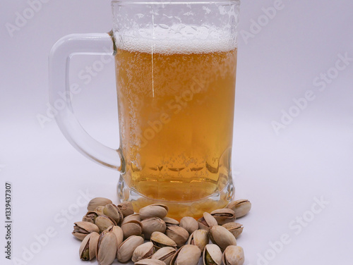 Glass of wheat beer, scattered pistachios, on a white background, close-up