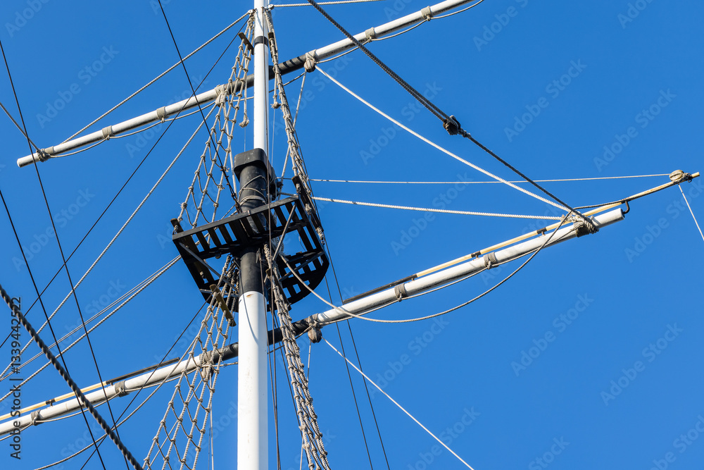 White ships mast, black platform, and rigged ropes are under blue sky White ships mast, black platform, and rigged ropes are under blue sky
