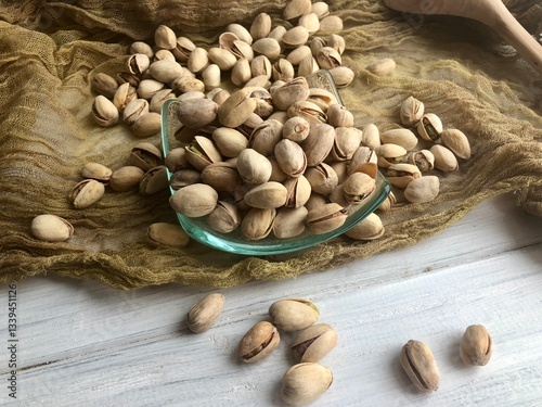 Delicious pistachios in glass bowl on table, closeup/ perfect beer snacks