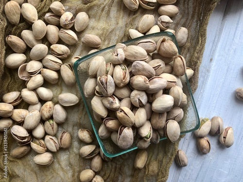 Delicious pistachios in glass bowl on table, closeup/ perfect beer snacks