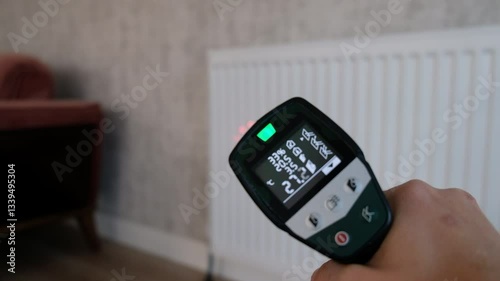 Checking Radiator Temperature with Infrared Thermometer in Living Room with Sofa