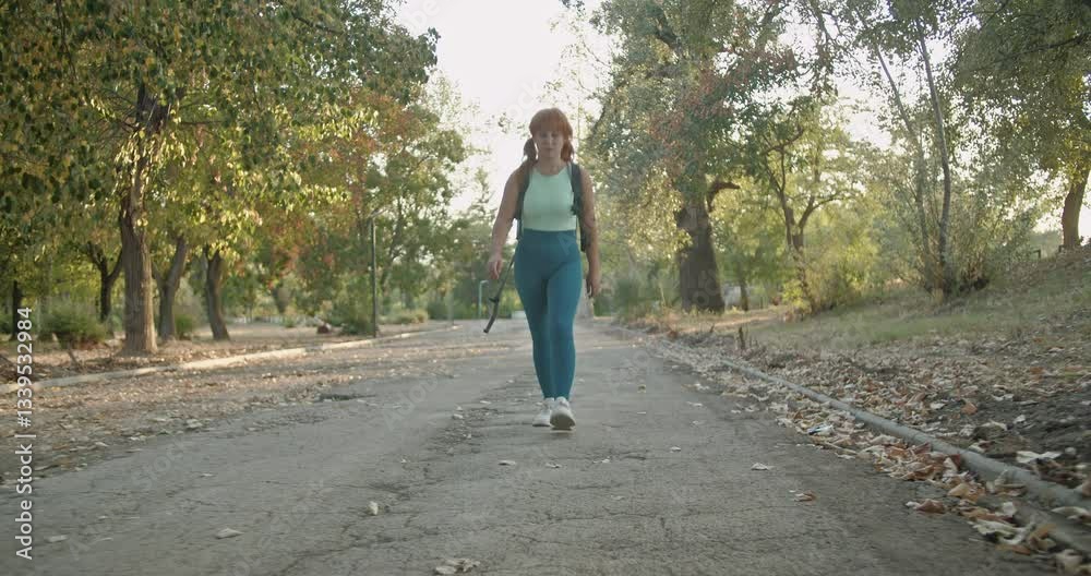 A young woman with a backpack walks through a peaceful park on a sunny day, enjoying the fresh air and tranquility. A young woman with a backpack walks through a peaceful park on a sunny day, enjoying the fresh air and tranquility.