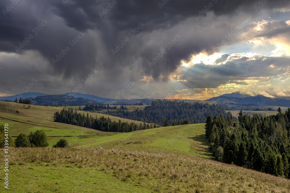 Dramatic clouds gather over rolling hills and lush forests before sunset in a tranquil landscape