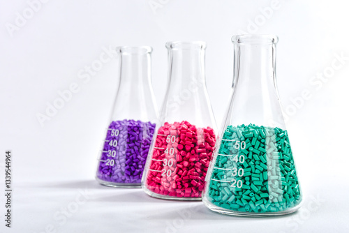 Red, purple and turquoise masterbatch granules in Erlenmeyer flask isolated on white background, color pigment carrier polymer in plastic industry. Perfect for plastic company catalog design