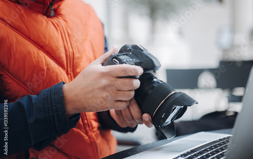 Photographer reviewing photos on professional camera and laptop, working on photo editing and post production