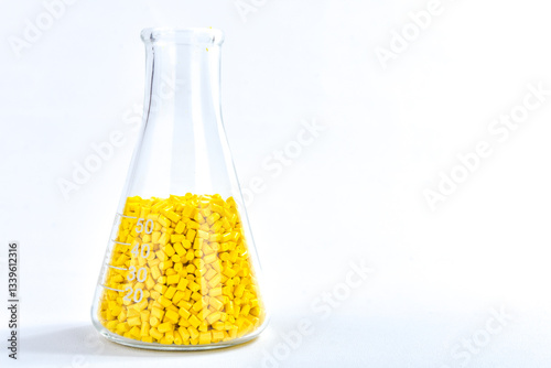 Yellow masterbatch granules in Erlenmeyer flask isolated on white background, color pigment carrier polymer in plastic industry. Perfect for plastic company catalog design