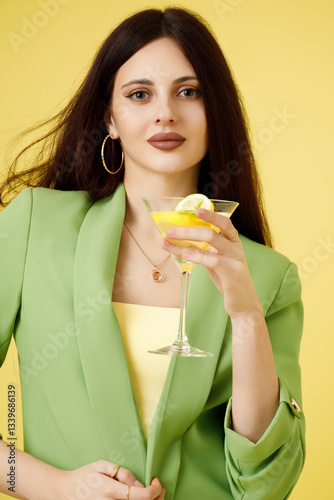 Obraz na płótnie Fashion portrait of beautiful model in green suit with glass of lemonade against yellow background w salonie