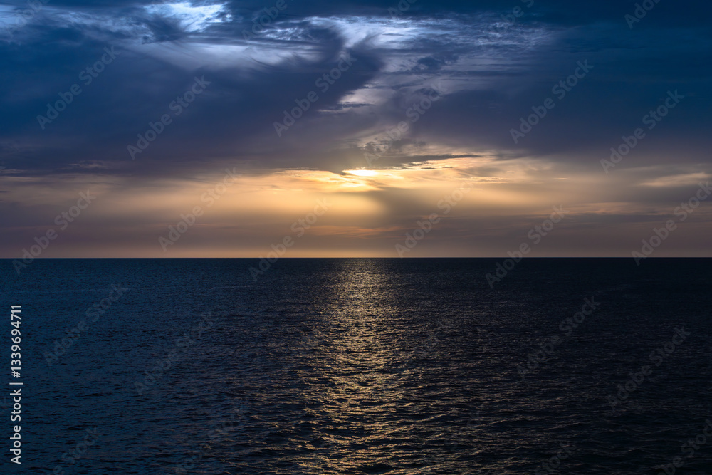 Tranquil sea sunset with dramatic clouds and reflections Tranquil sea sunset with dramatic clouds and reflections