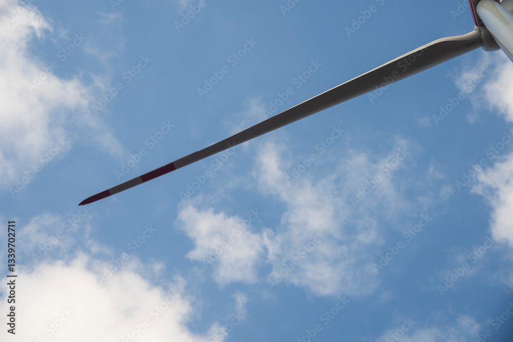 A wind turbine with a blue sky and clouds. Concept of clean energy. A wind turbine with a blue sky and clouds. Concept of clean energy.