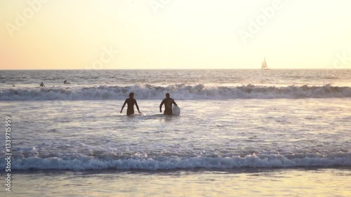 Surfers Entering Ocean at Sunset in Slow Motion