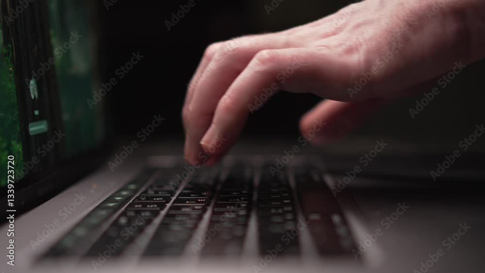 Focused hands expertly typing on a laptop keyboard illuminated by dim ambient light