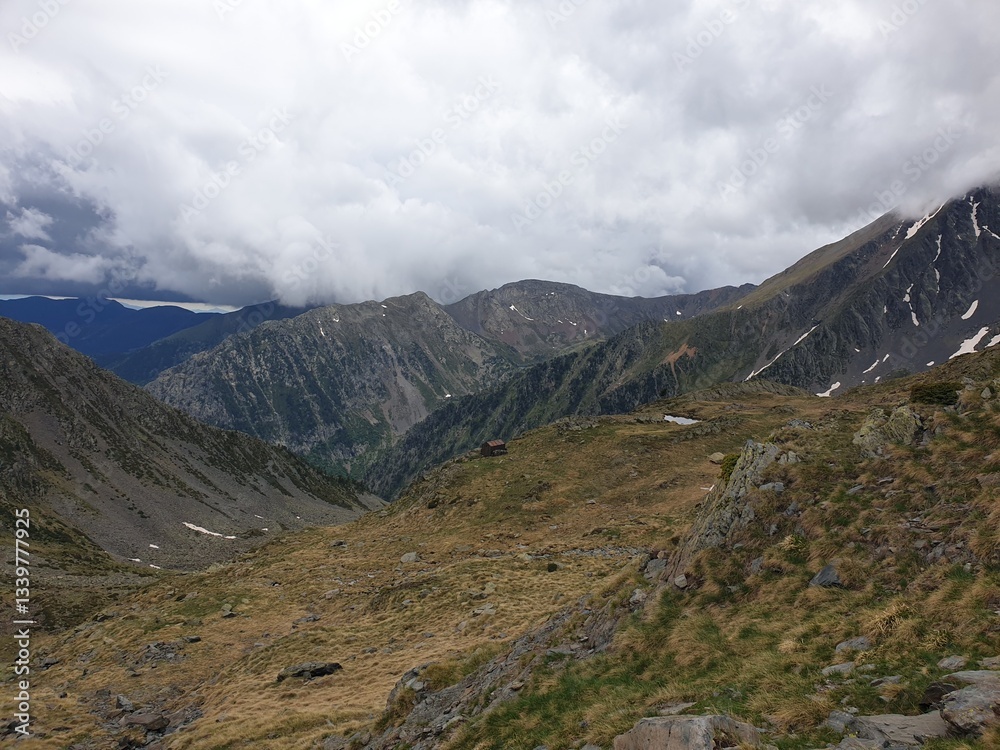 Obraz premium Picturesque landscape on the peak of the mountain with snow and green grass at summer, cloudy in the mountains of Andorra, Arinsal