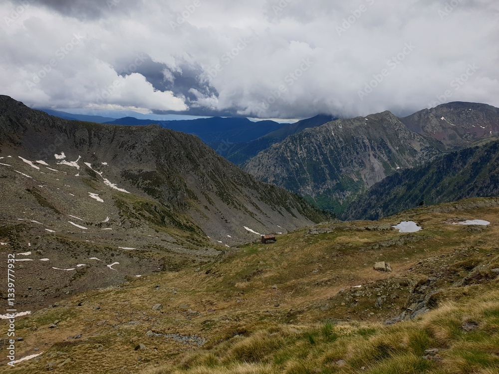 Picturesque landscape on the peak of the mountain with snow and green grass at summer, cloudy in the mountains of Andorra, Arinsal Picturesque landscape on the peak of the mountain with snow and green grass at summer, cloudy in the mountains of Andorra, Arinsal
