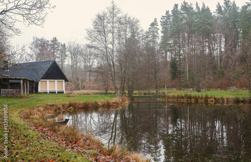 Swedish forest cabin by a reflective pond in the countryside. Black traditional swedish house 